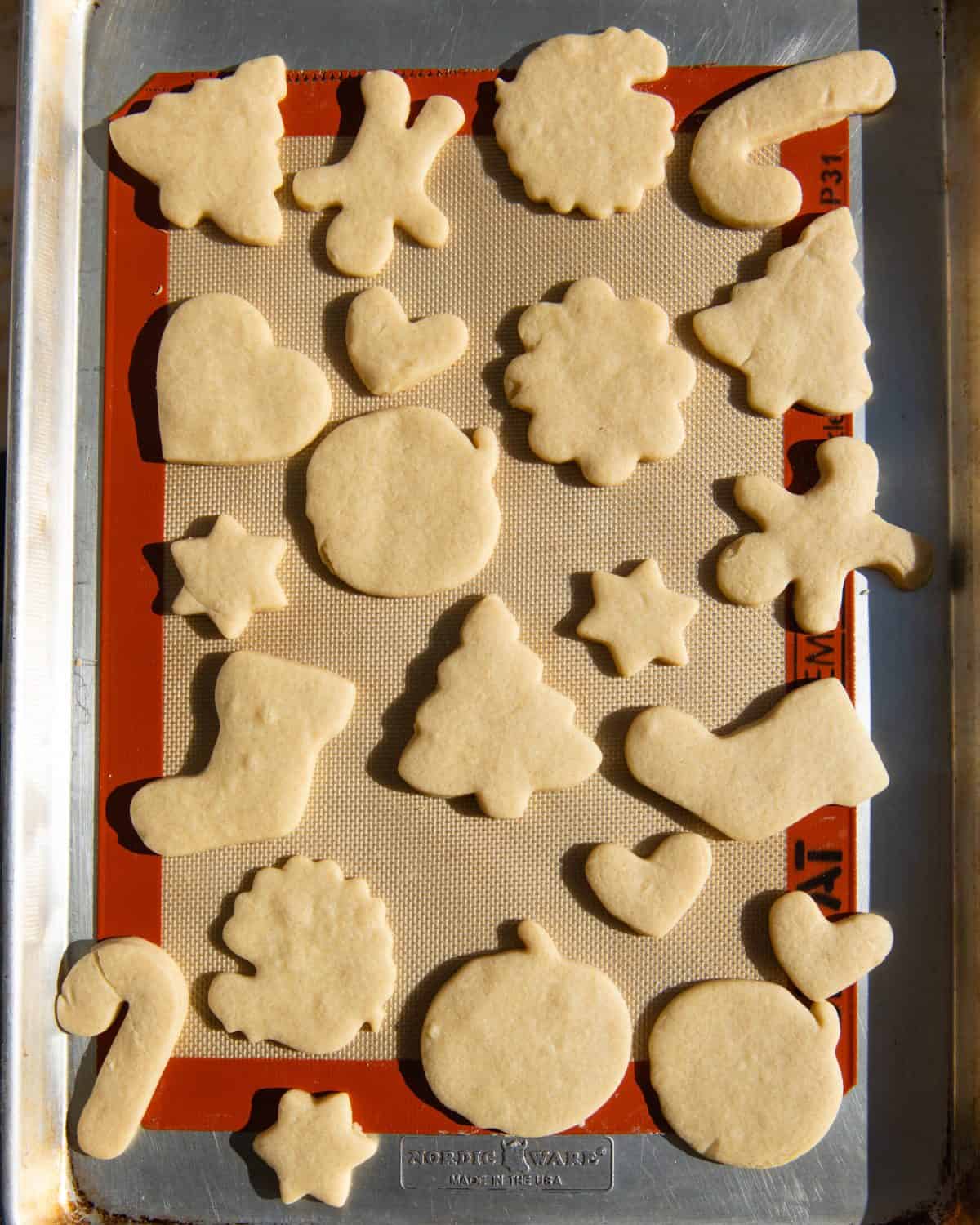 cut out sugar cookies on a baking sheet lined with a silicone baking mat after baking. Cut into shapes like hearts, turkeys, Christmas trees, gingerbread men, stockings, pumpkins, stars and more.