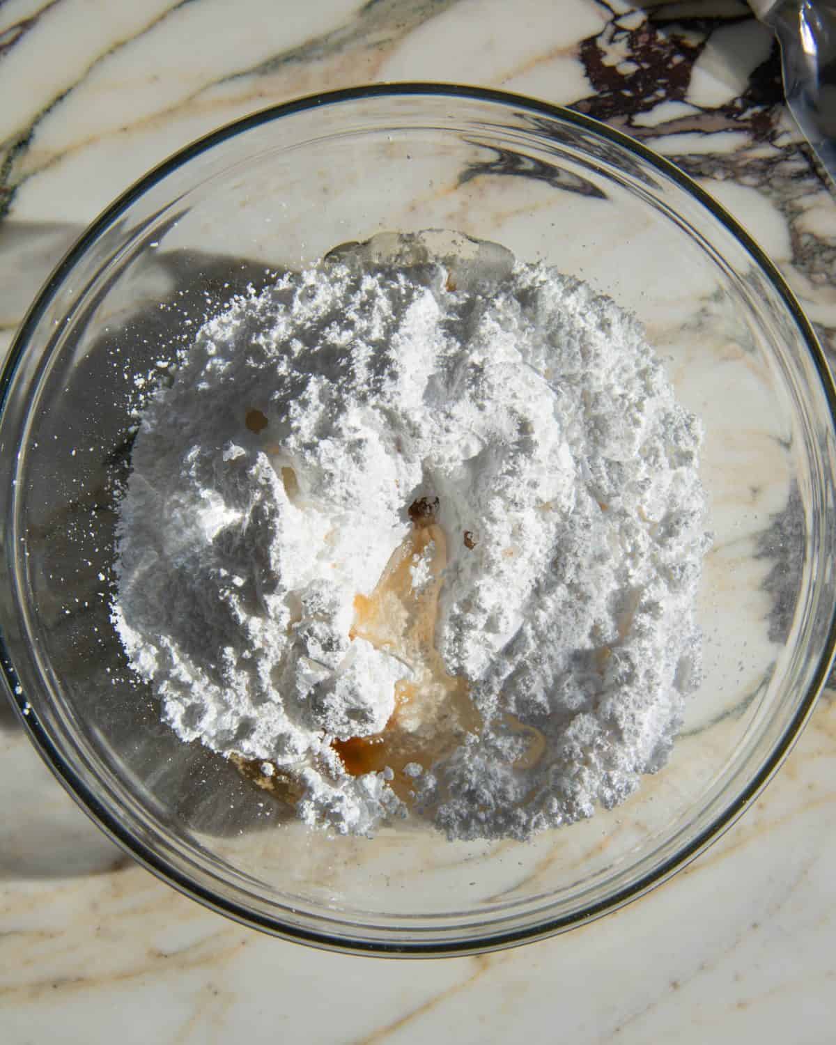 sugar cookie frosting ingredients in a glass bowl on a marble surface before mixing