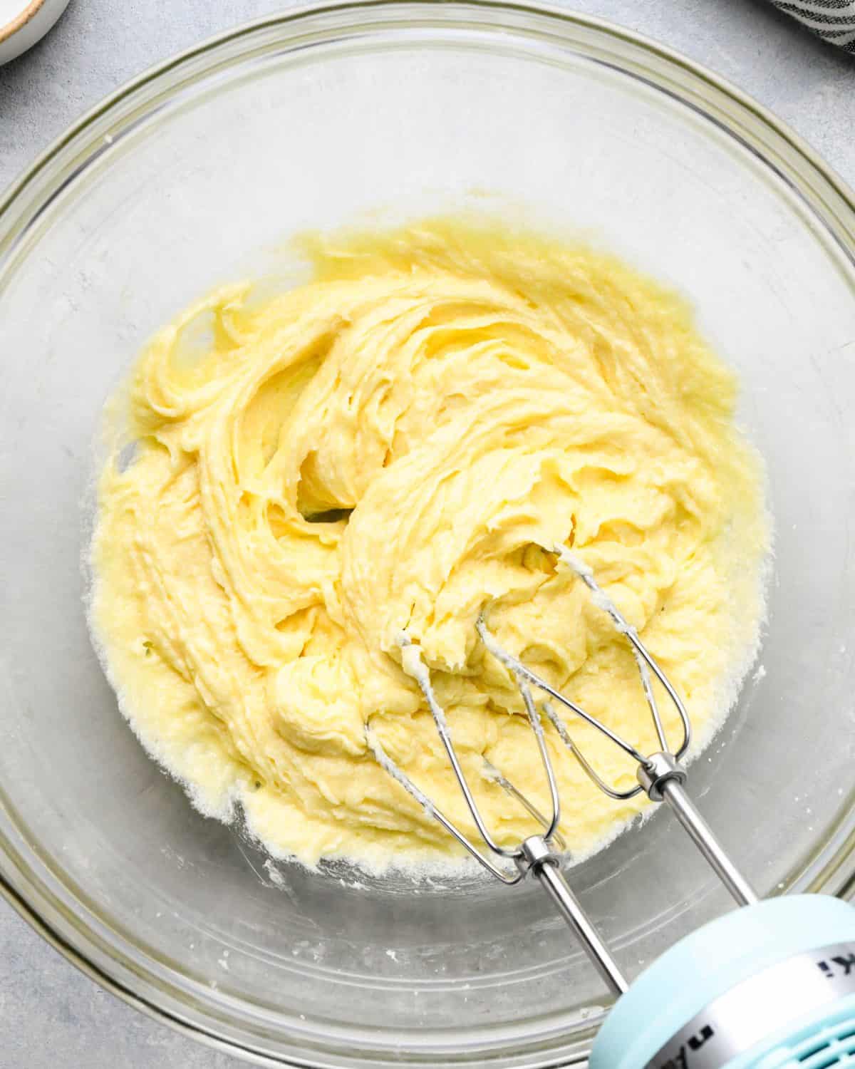 making snickerdoodles - wet ingredient mixture in a glass mixing bowl with a small blue hand mixer with two beaters after mixing