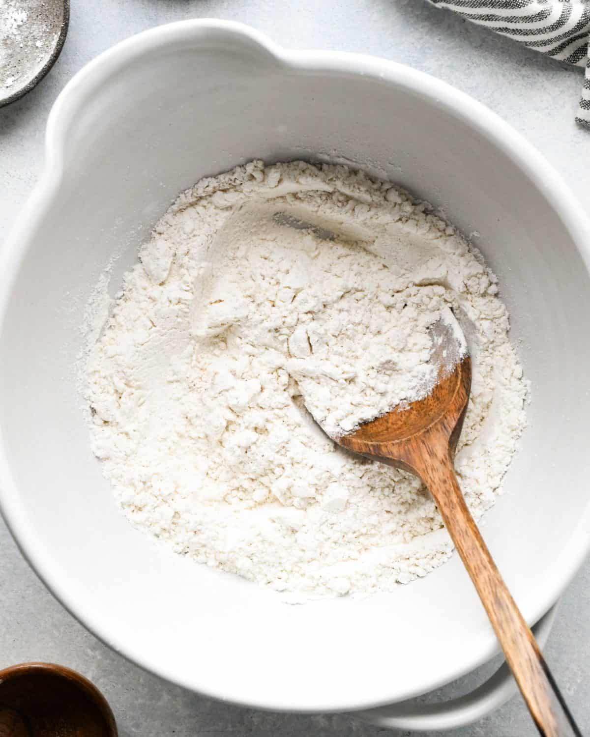 making snickerdoodles - flour mixture stirred together with a wooden spoon in a white ceramic bowl