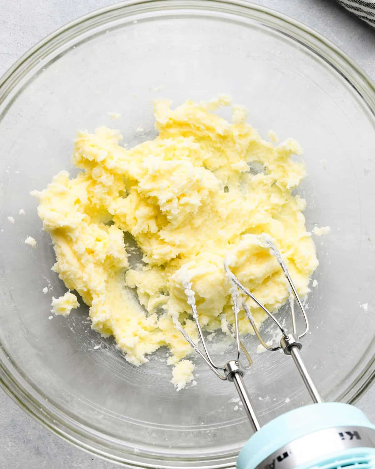 making snickerdoodles - butter sugar and shortening in a glass mixing bowl after being beaten together with a small blue hand mixer with two beaters.