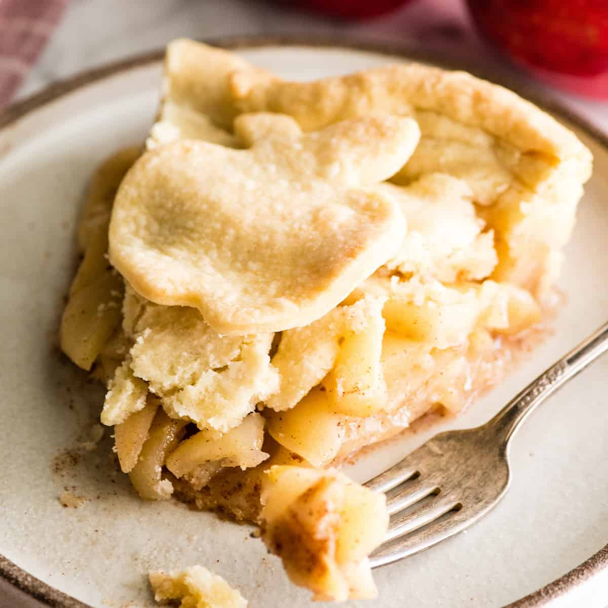 piece of apple pie on a plate with a fork taking a bite