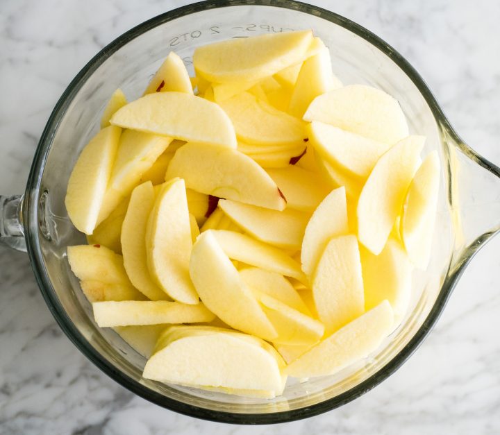 overhead view of a glass bowl of peeled and cut apples