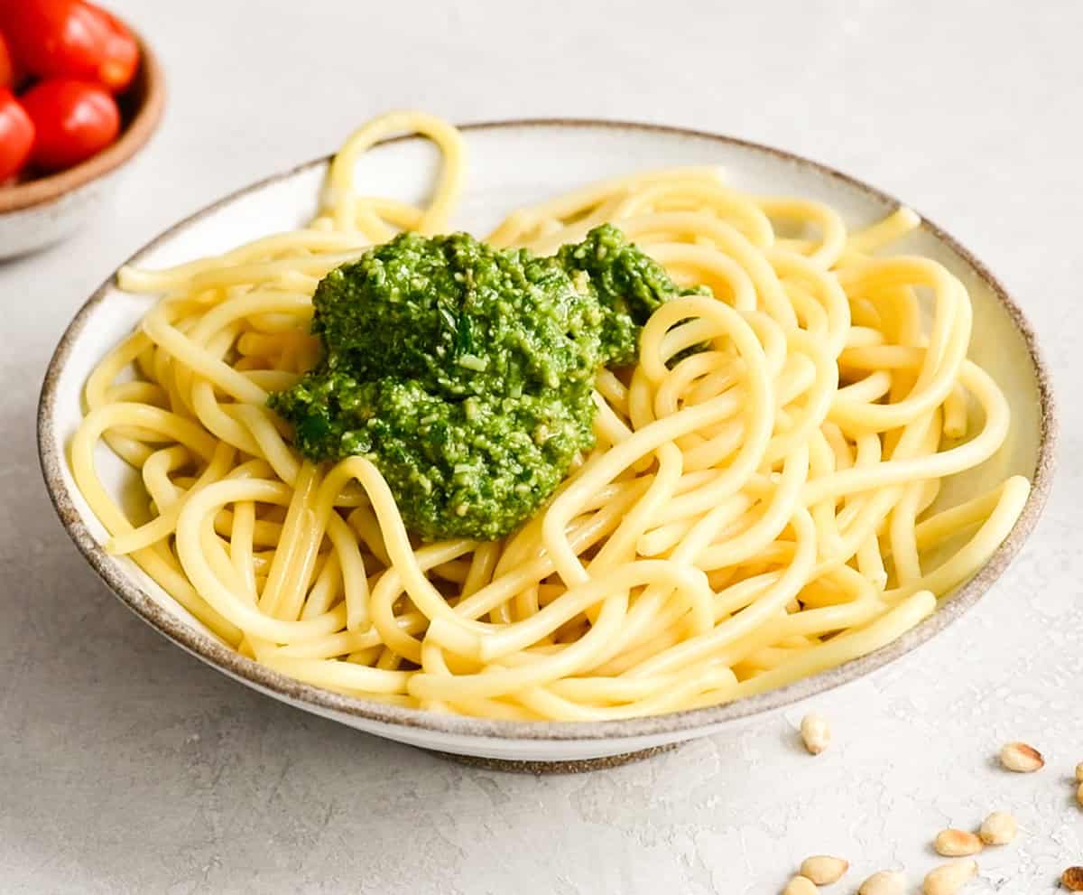front view of a homemade pesto sauce on bowl of spaghetti noodles to make Pesto Pasta before mixing in