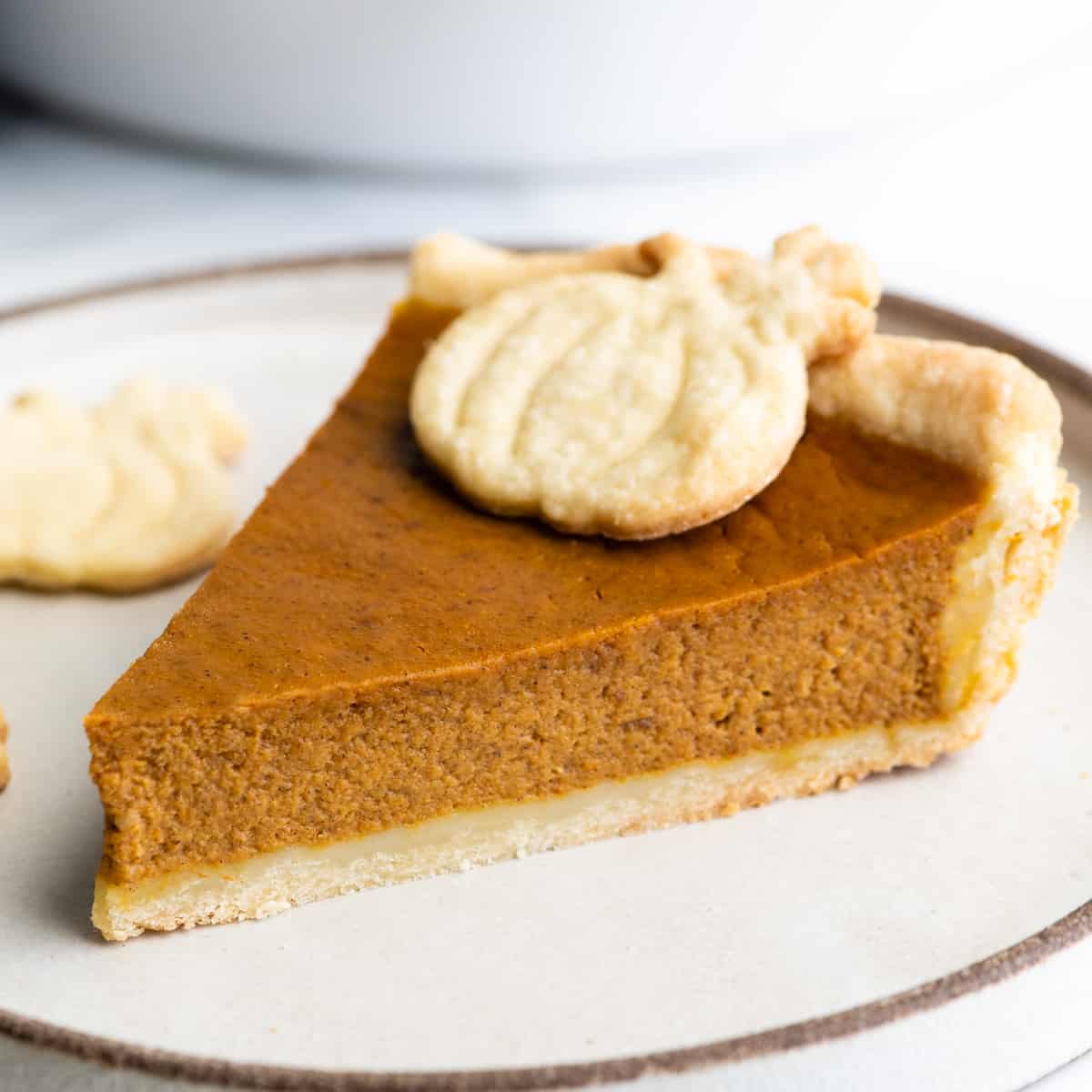front view of a slice of Pumpkin Pie on a plate with a pie crust pumpkin on top 