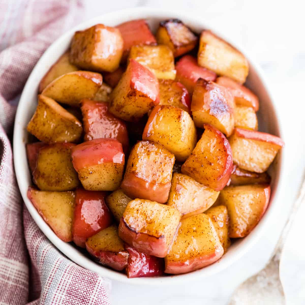 overhead photo of cinnamon apples in a white bowl