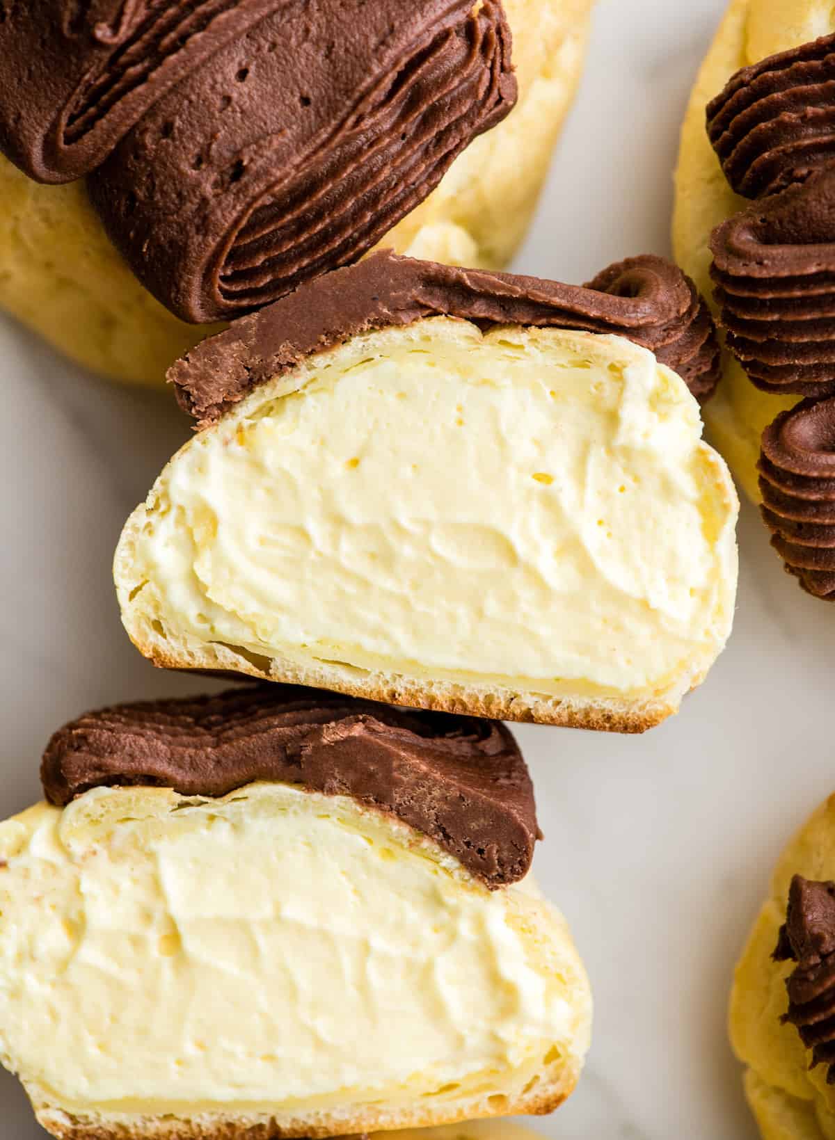 overhead view of two halves of a homemade eclair laying down so you can see the filling inside.