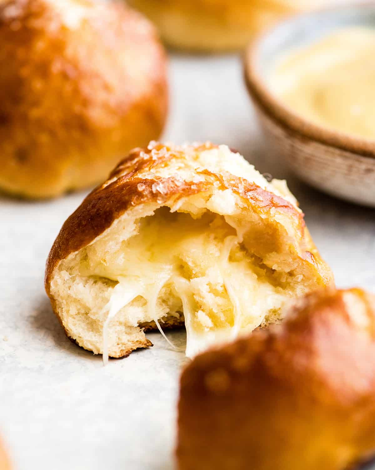 front view of a cheese-stuffed pretzel bite cut in half so the cheese in the center is visible