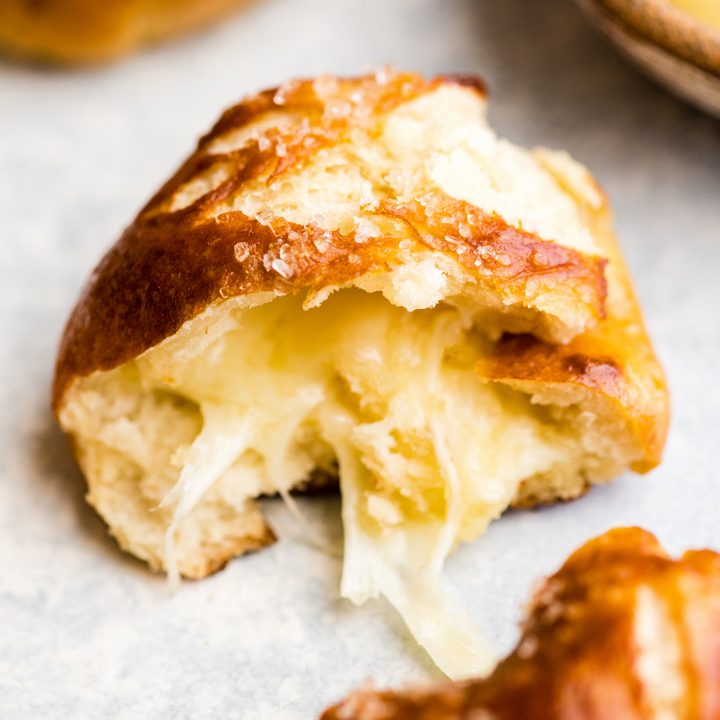 front view of a cheese-stuffed pretzel bite cut in half so the cheese in the center is visible