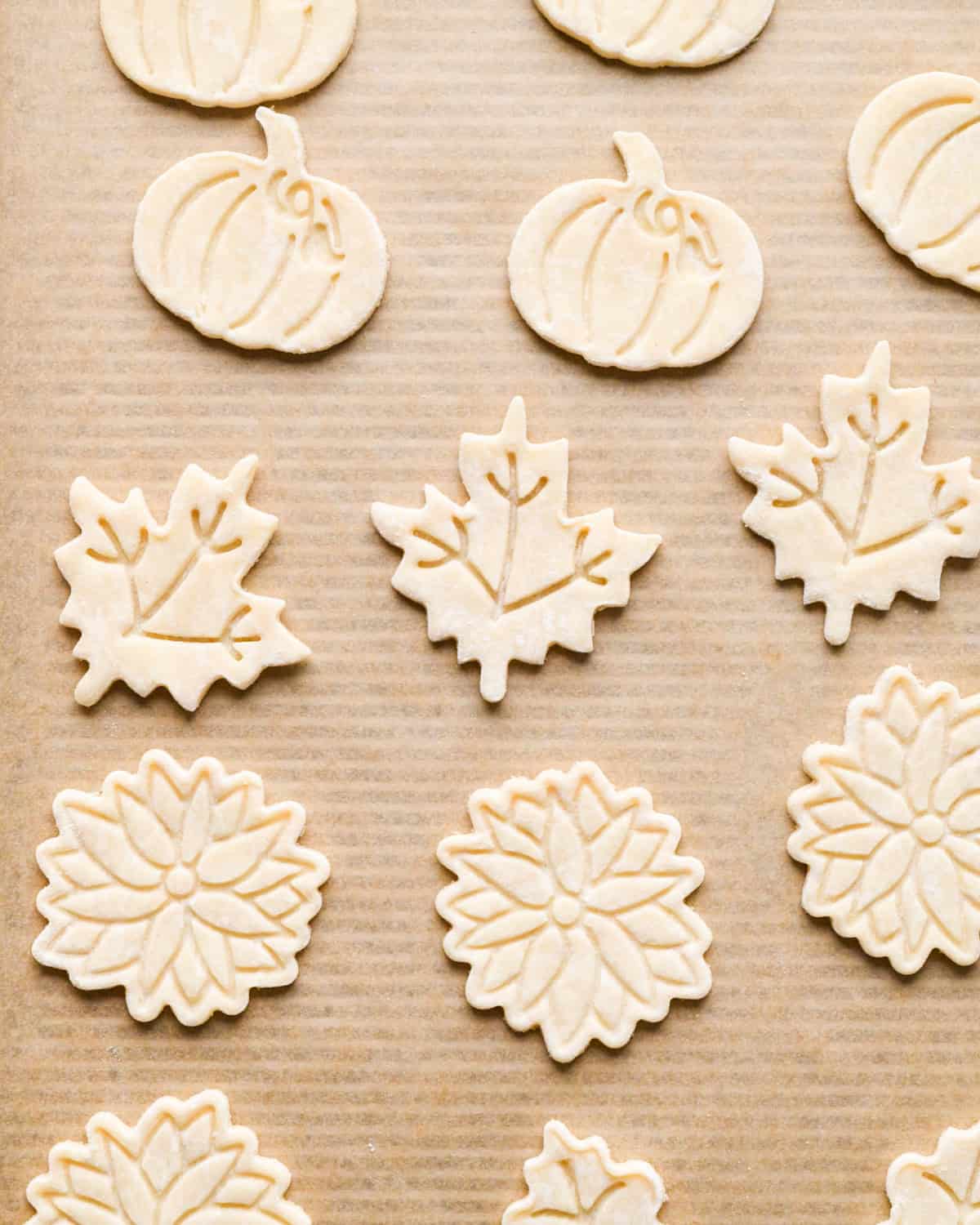 pumpkin, leaf and flower pie crust shapes on a baking sheet lined with parchment paper before baking
