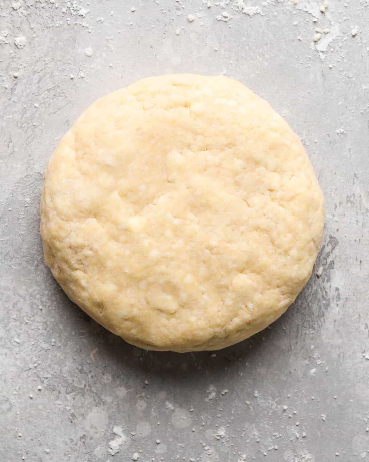 a round disc of pie crust dough on a gray surface