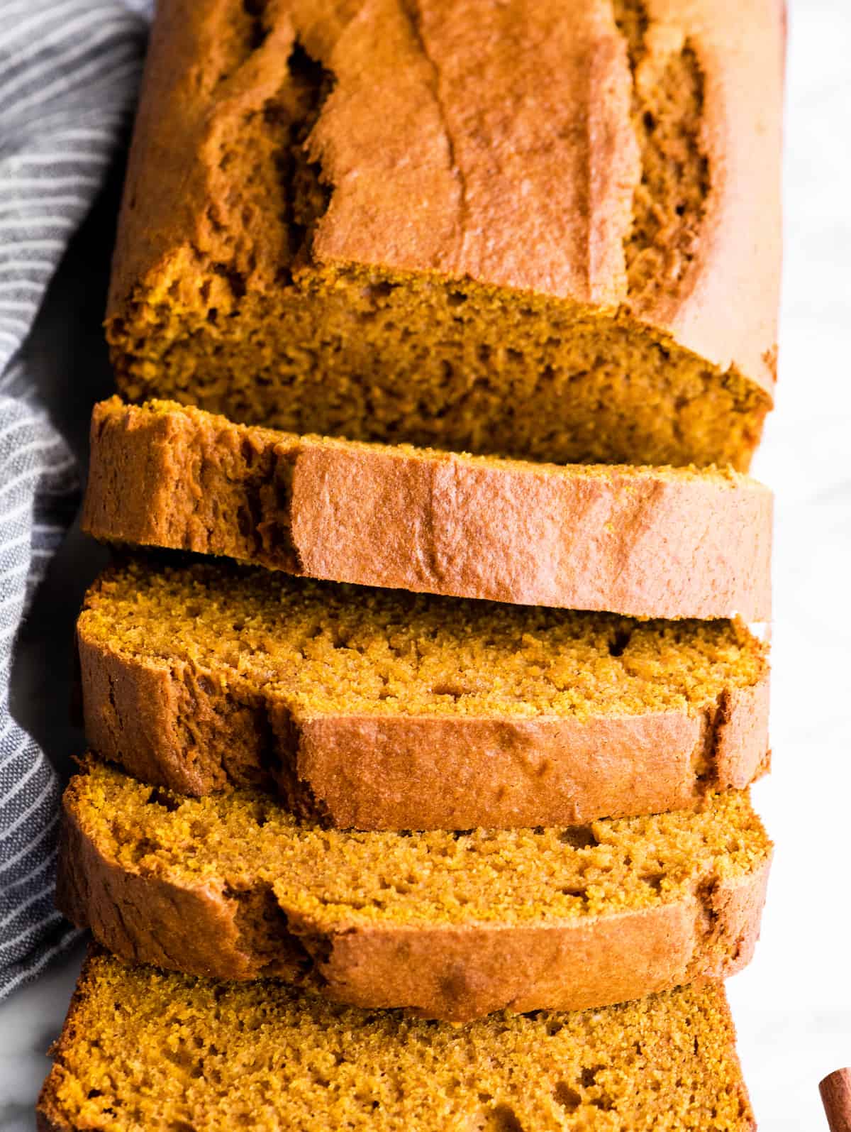 up close overhead view of a loaf of pumpkin bread with 4 slices cut out of it