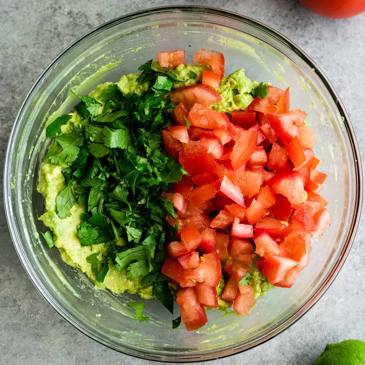 photo showing How to make Guacamole - adding cilantro, tomato and onion 