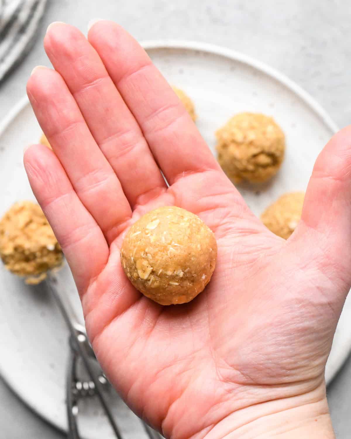 a hand rolling oatmeal cookie dough balls