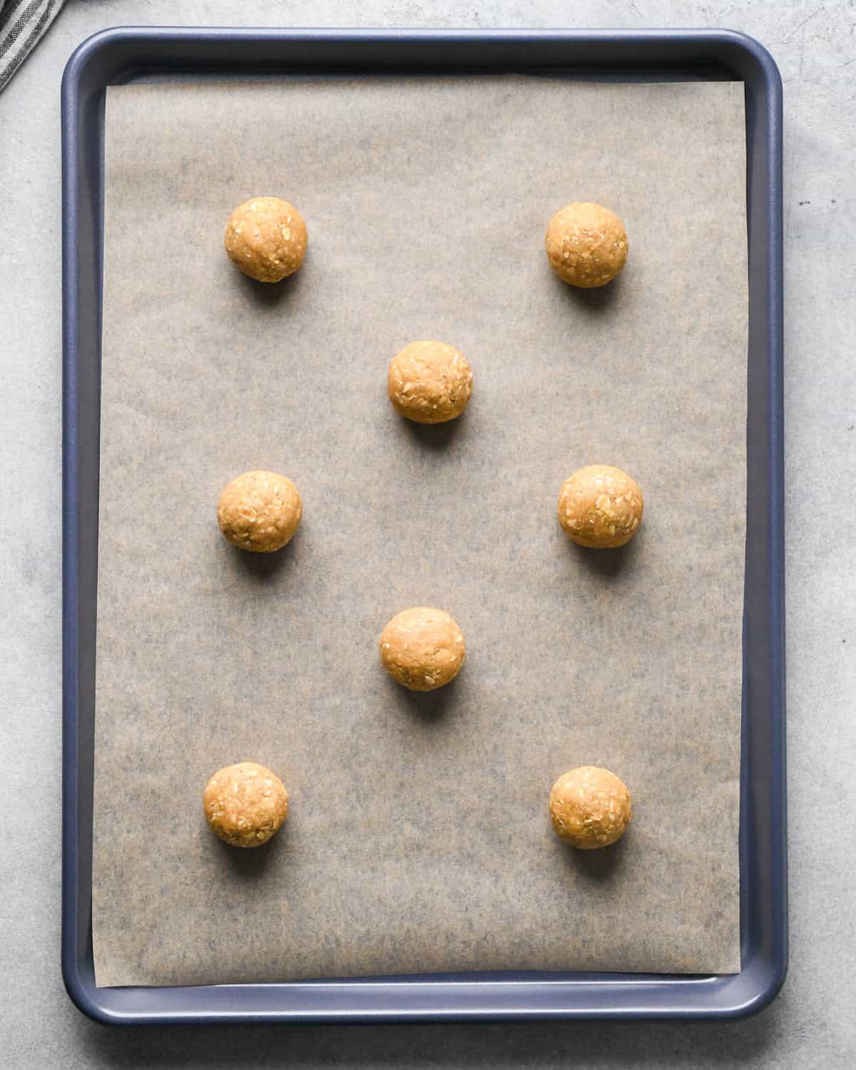 8 oatmeal cookie dough balls on a baking sheet before baking