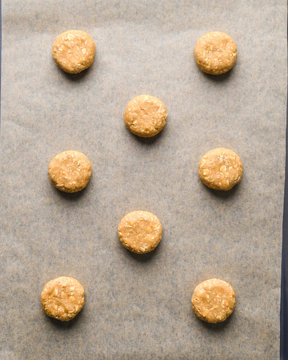 8 oatmeal cookies on a baking sheet lined with parchment paper before baking