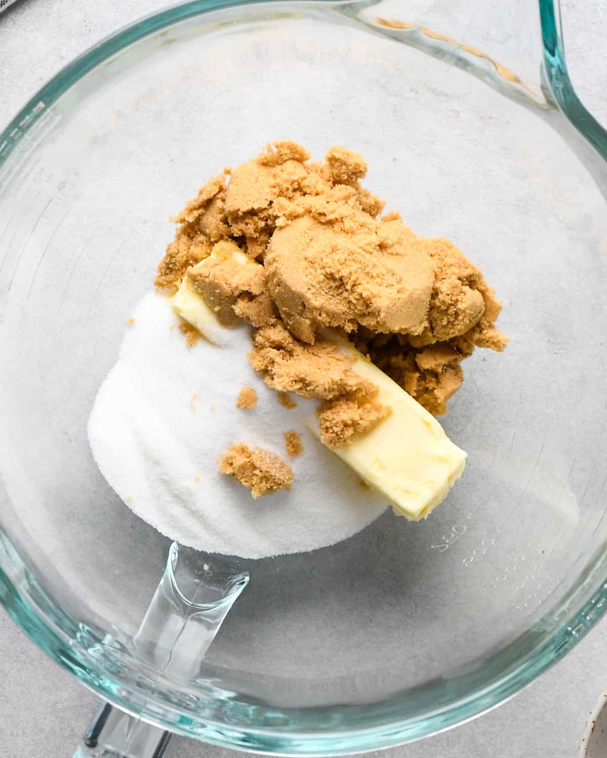 a bowl containing butter, brown sugar and white sugar before mixing while making oatmeal cookies