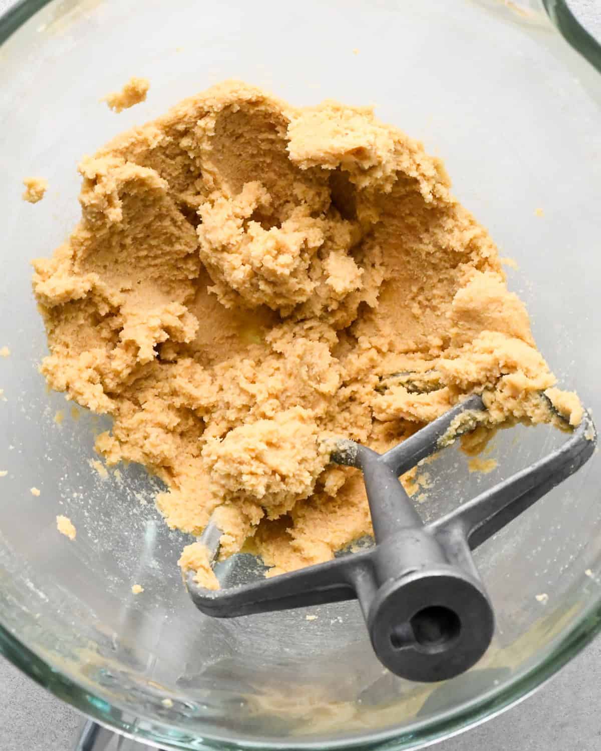 a bowl containing beaten butter, brown sugar and white sugar to make oatmeal cookies