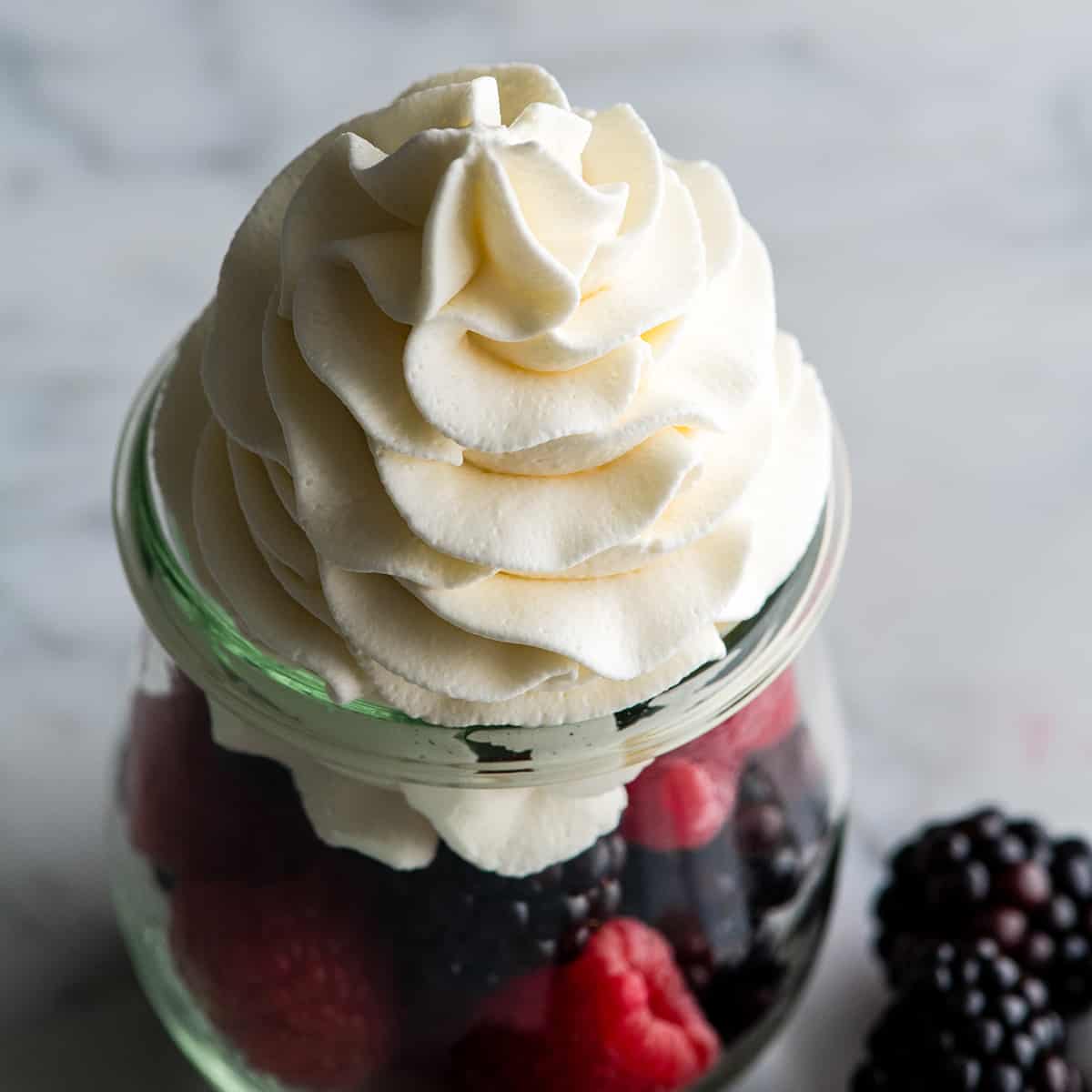 Overhead view of homemade whipped cream piped on top of fresh berries