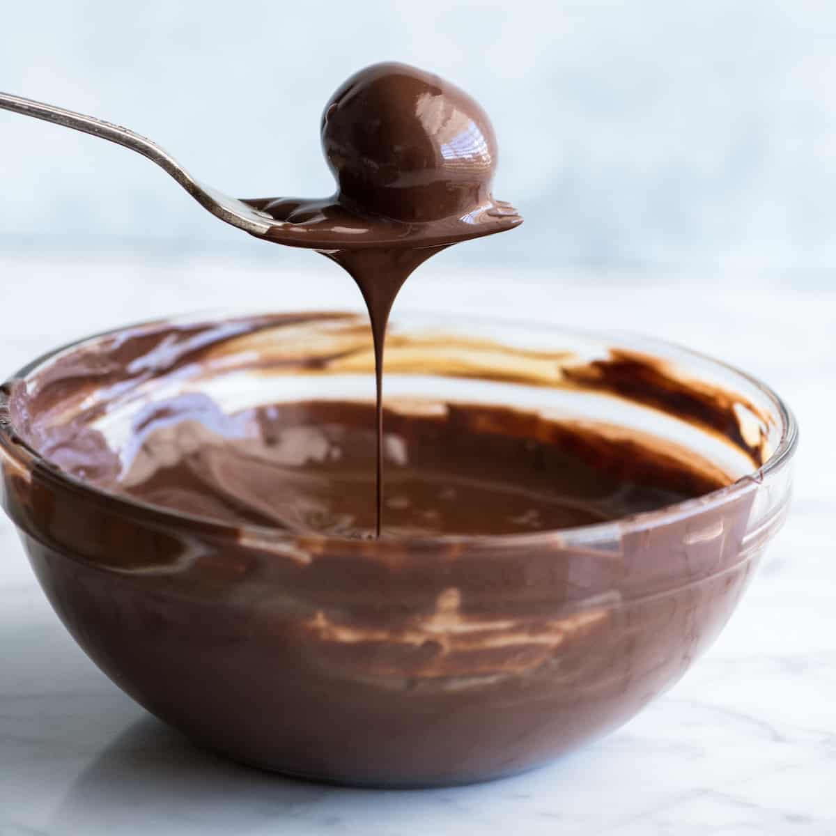 front view of a peanut butter ball being dipped in chocolate