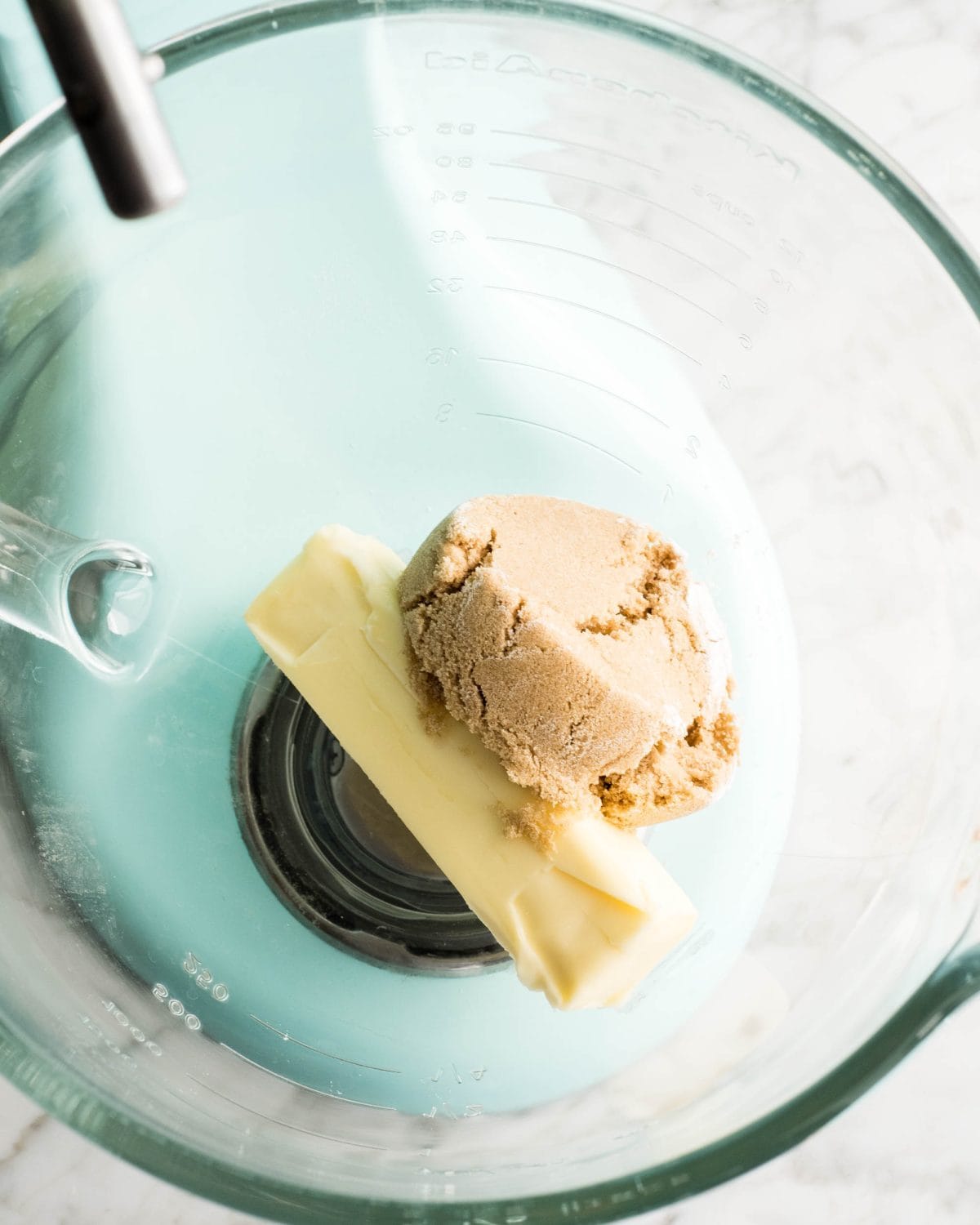 making soft gingerbread cookies - a stick butter and light brown sugar in a glass mixing bowl of a light blue standing mixer before beating together