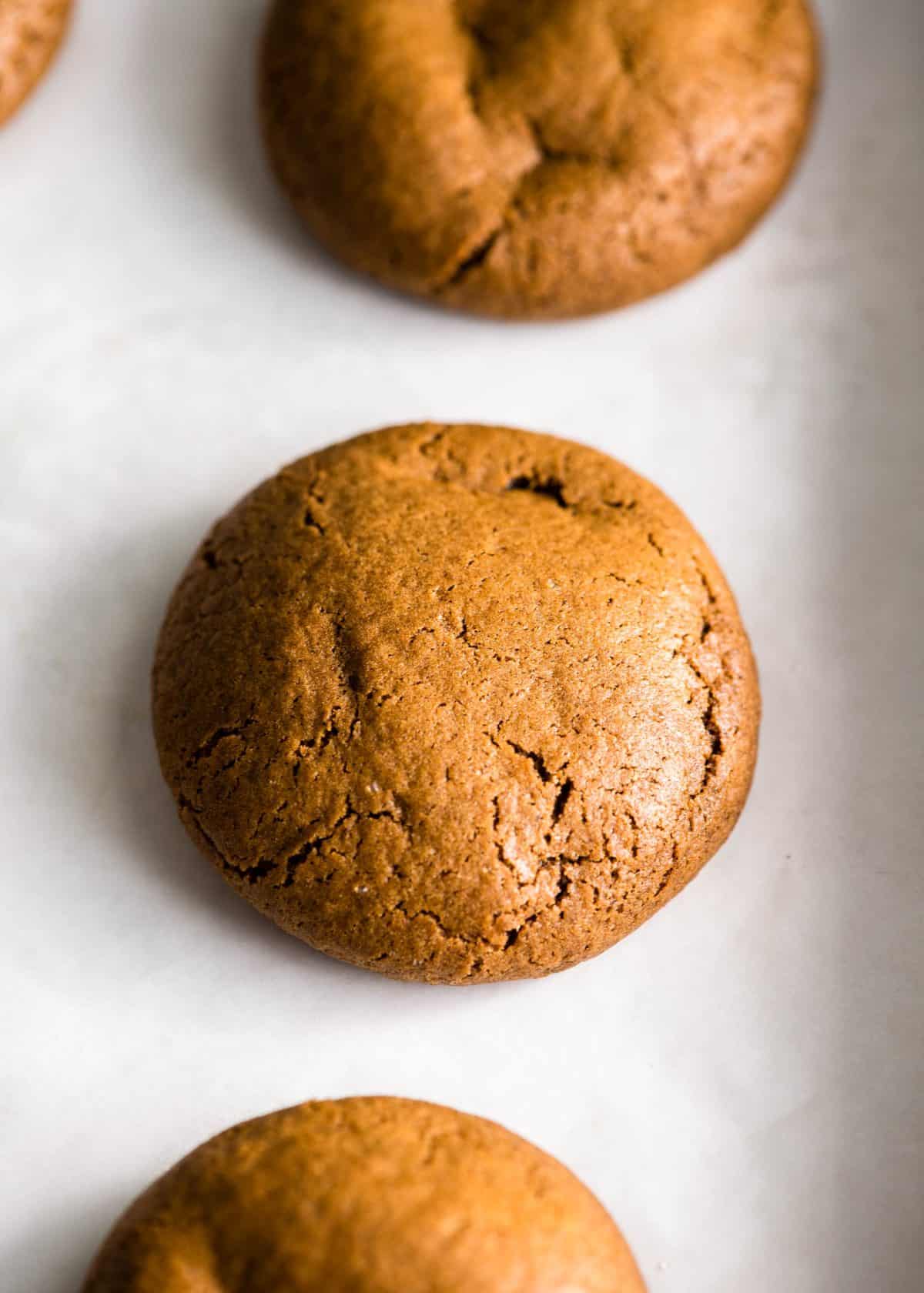 3 soft gingerbread cookies in a parchment paper lined baking sheet after baking