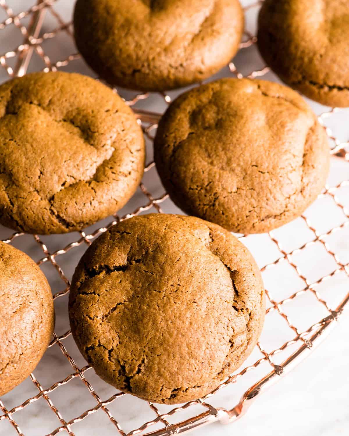 6 easy gingerbread cookies on a copper wire cooling rack after baking.