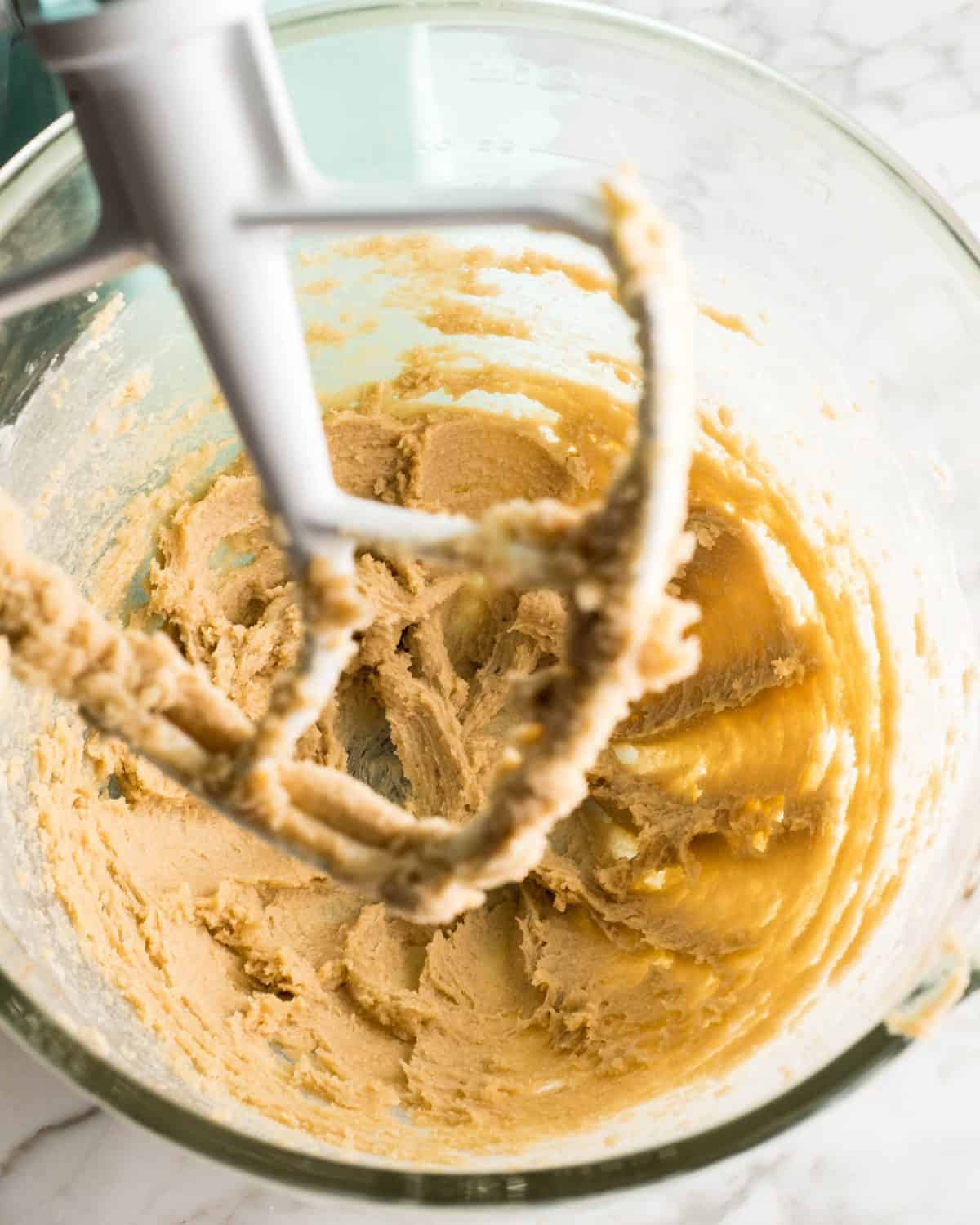 making soft gingerbread cookies - a stick butter and light brown sugar in a glass mixing bowl of a light blue standing mixer fitted with the white paddle attachment after beating together