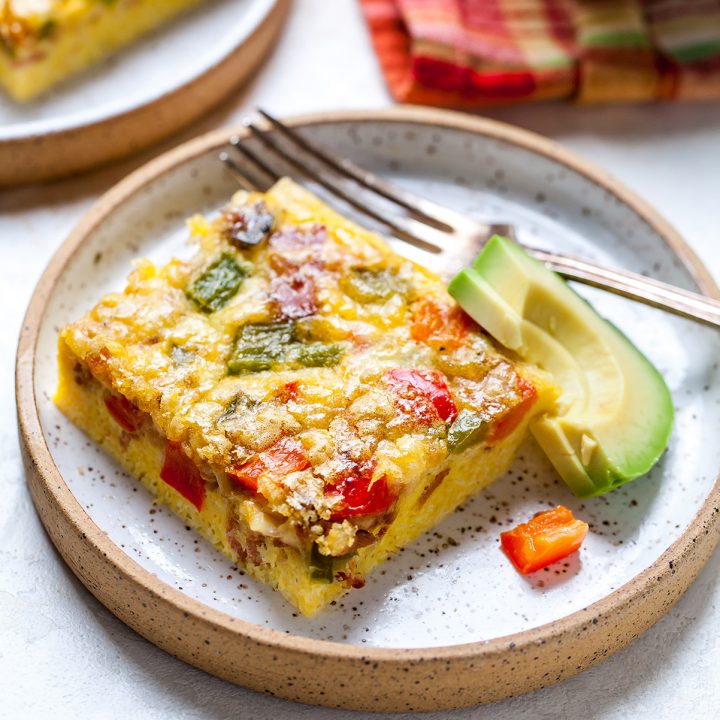 square piece of egg casserole on a plate with avocado and a fork