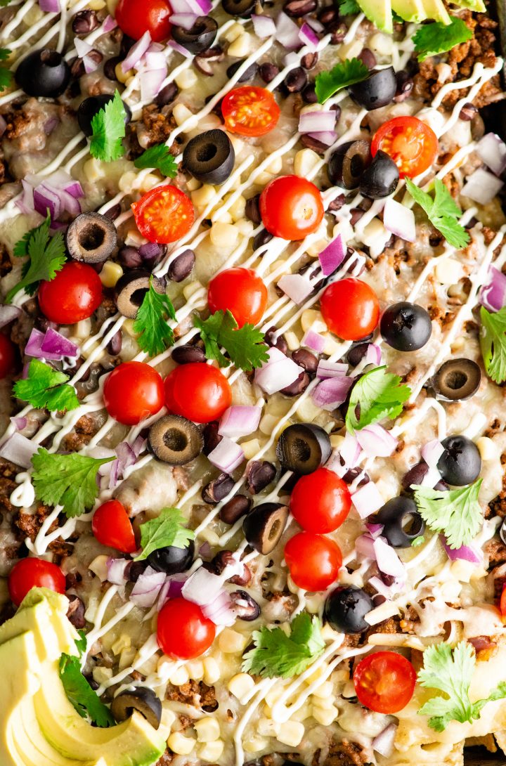 overhead view of best nachos recipe in a sheet pan with nacho toppings