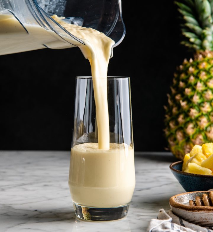front view of a pineapple smoothie being poured into a glass