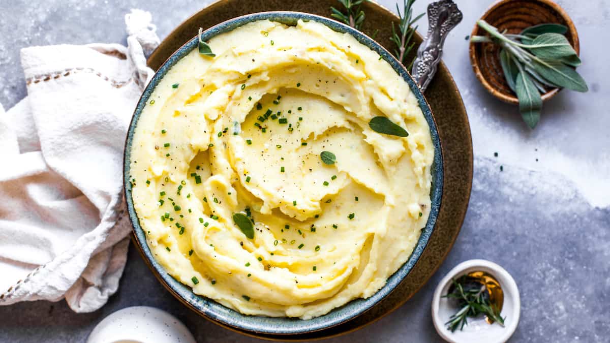 Overhead view of mashed potatoes in a bowl topped with fresh herbs