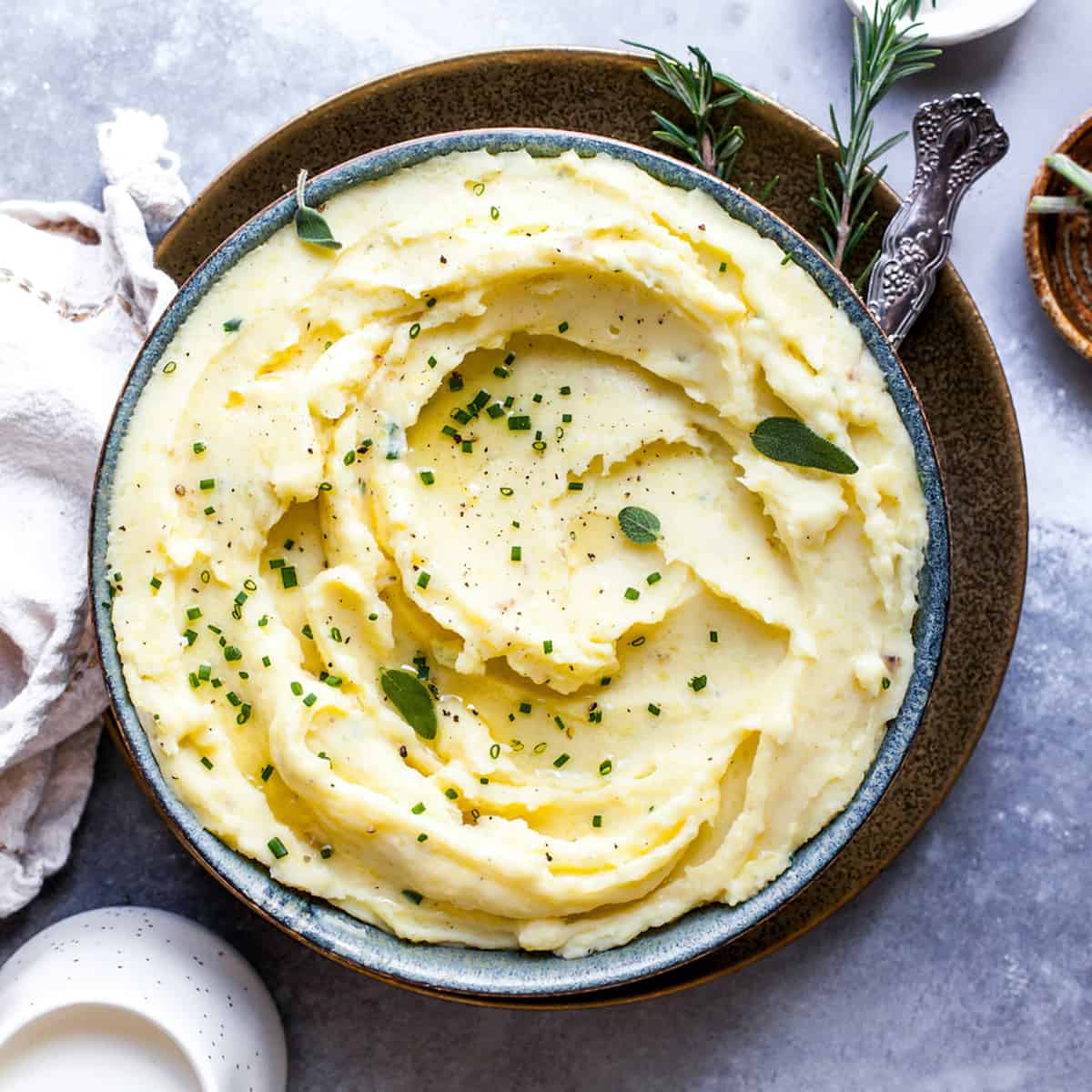 Overhead view of mashed potatoes in a bowl topped with fresh herbs