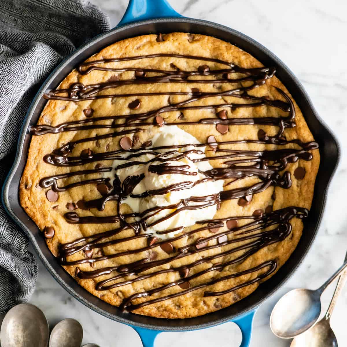 overhead view of a skillet cookie (pizookie) drizzled with chocolate topped with ice cream