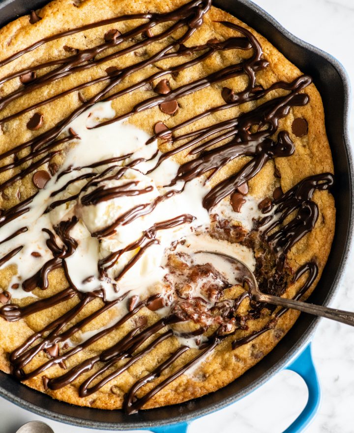 overhead view of a skillet cookie (pizookie) drizzled with chocolate topped with ice cream