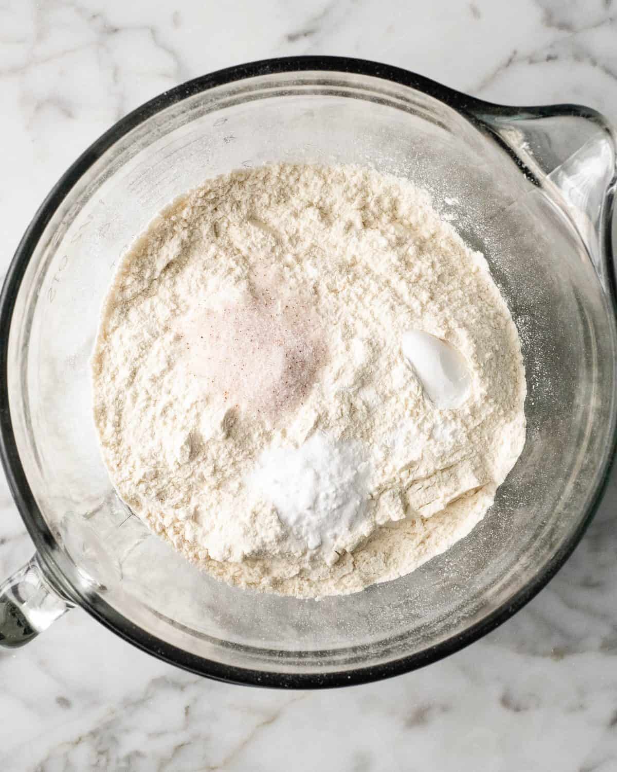 making double chocolate chip cookies - flour, baking soda, baking powder and salt in a glass batter bowl before mixing