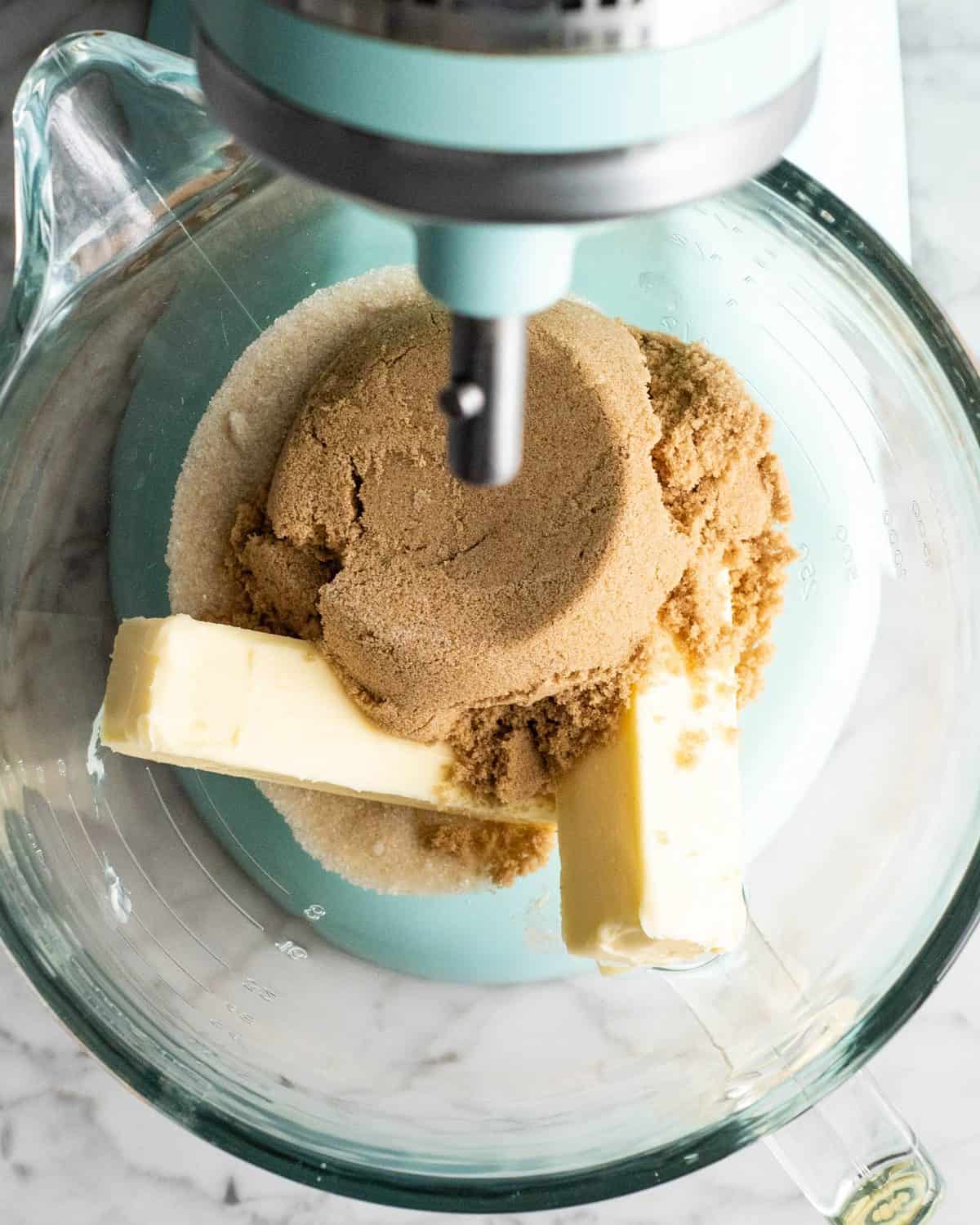 making double chocolate chip cookies - two sticks of butter, brown sugar and white sugar in a glass bowl of a light blue standing mixer before mixing