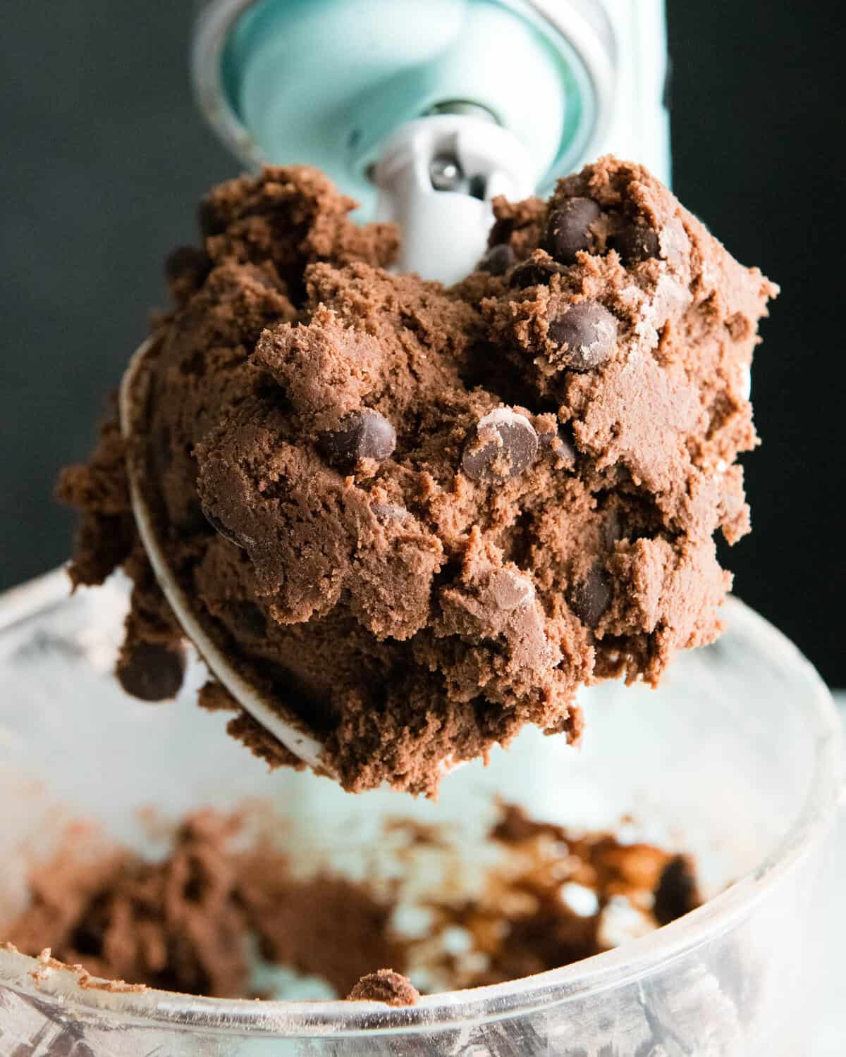 The BEST easy double chocolate chip cookie recipe ever! These chocolate cookies have soft centers, chewy edges and are irresistibly chocolatey. They come together in 5 minutes and require only 30 minutes of chilling time! #chocolate #cookies #chocolatecookies #baking #joyfoodsunshine making double chocolate chip cookies - finished dough in a glass bowl of a light blue standing mixer. a big chunk of dough is on the paddle attachment that is lifted out of the bowl