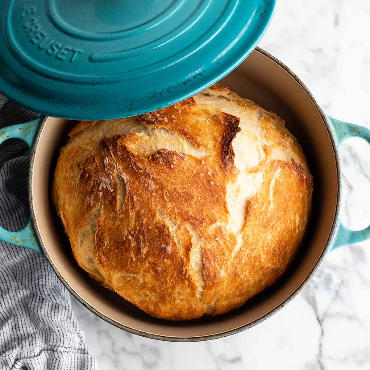 overhead view of baked dutch oven bread in a blue dutch oven