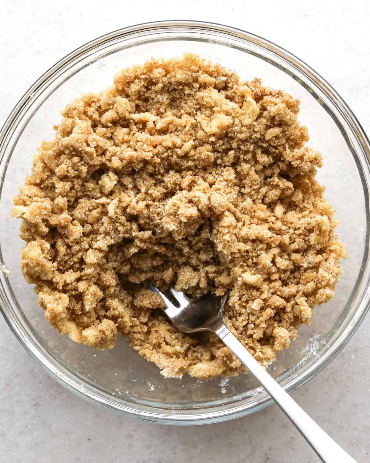 the crumb topping for blueberry muffins in a glass bowl with a silver fork after mixing