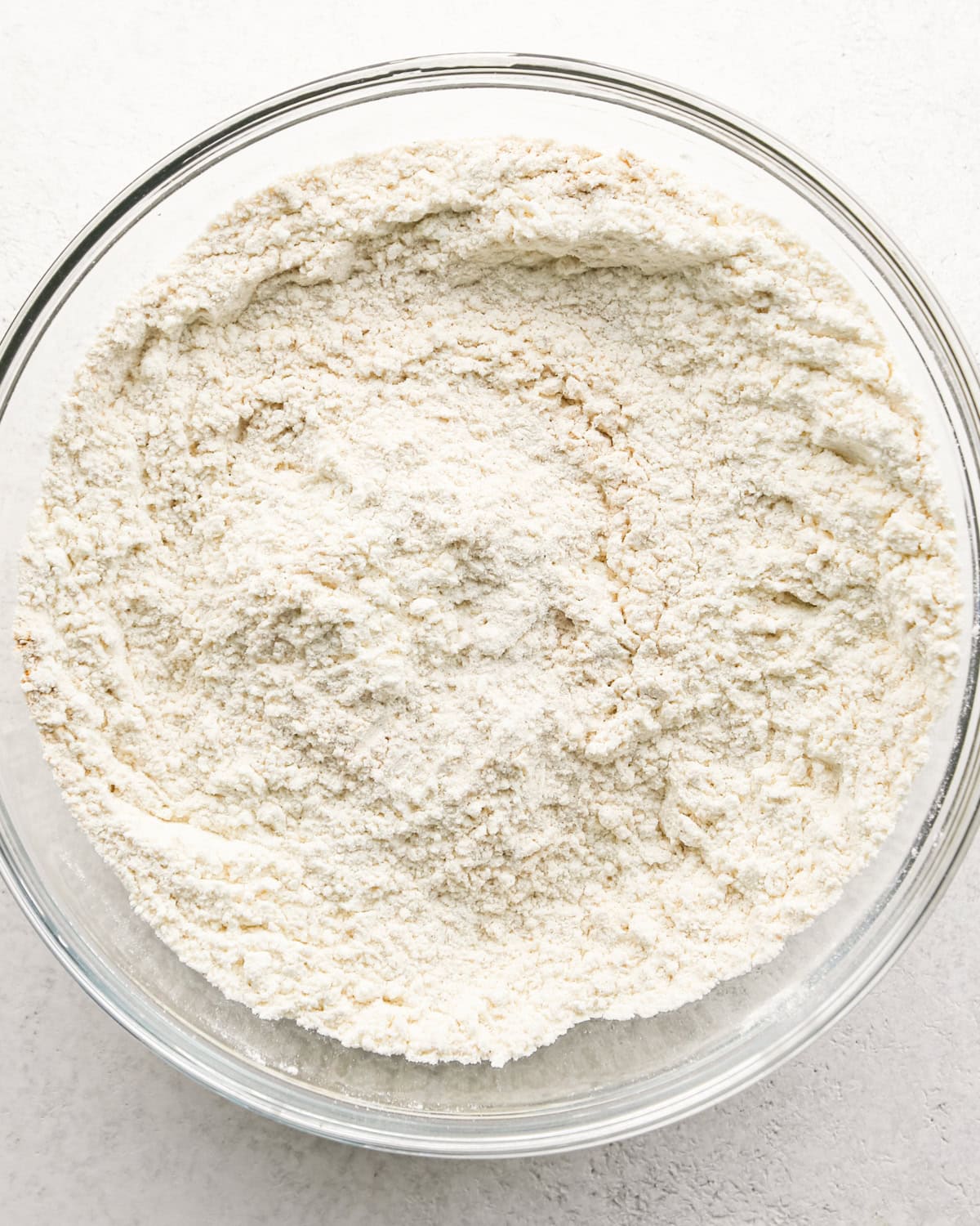 A glass bowl with the flour mixture after stirring, the dry ingredients for making banana cake.