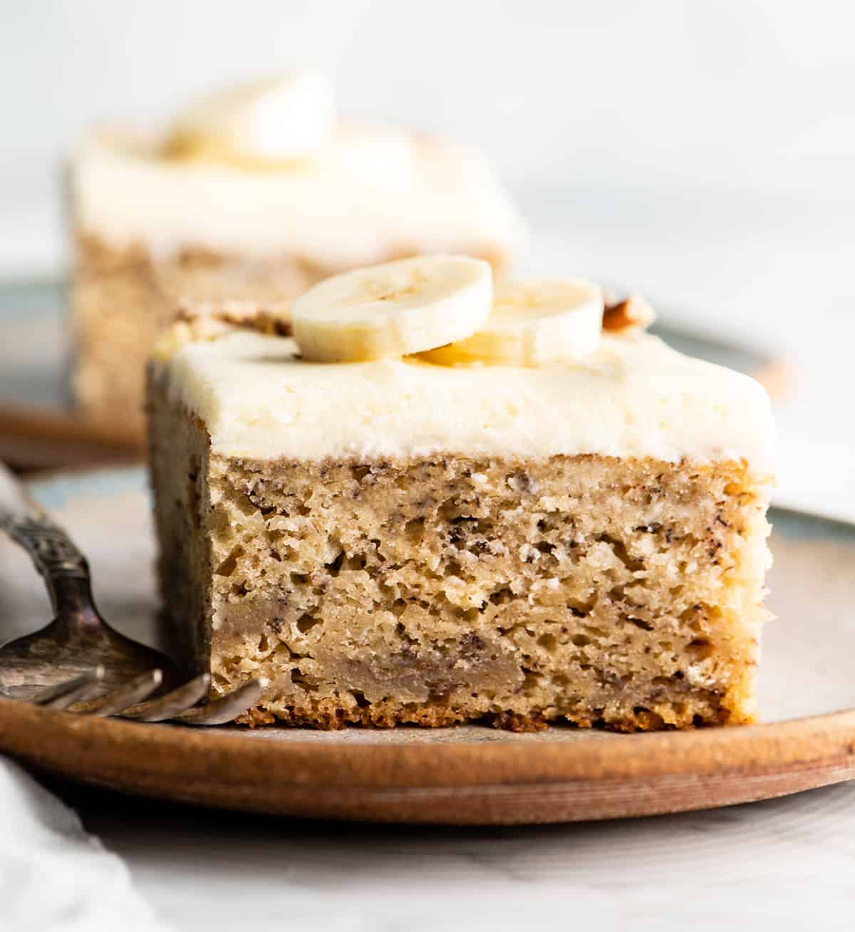 front view of a slice of banana cake with cream cheese frosting