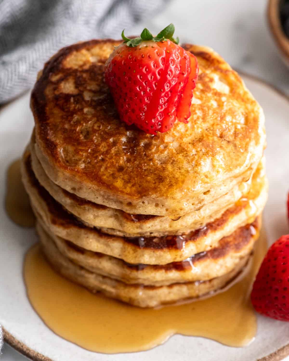 overhead view of a stack of 5 whole wheat pancakes with syrup and strawberries