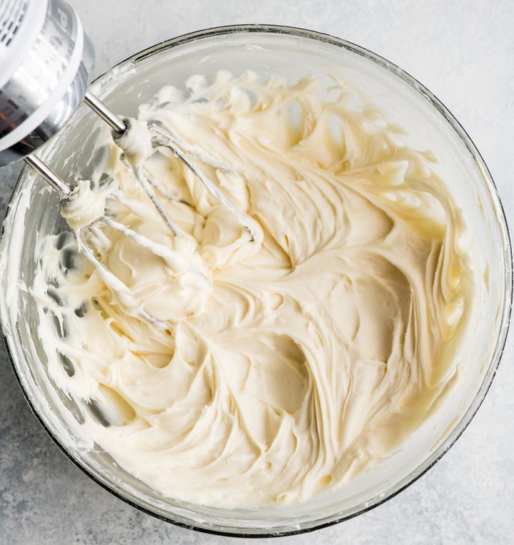 overhead photo showing how to make cream cheese frosting with a hand held mixer