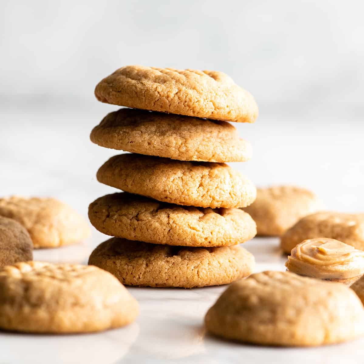 front view of a stack of 4 flourless peanut butter cookies with other cookies around the stack on the table