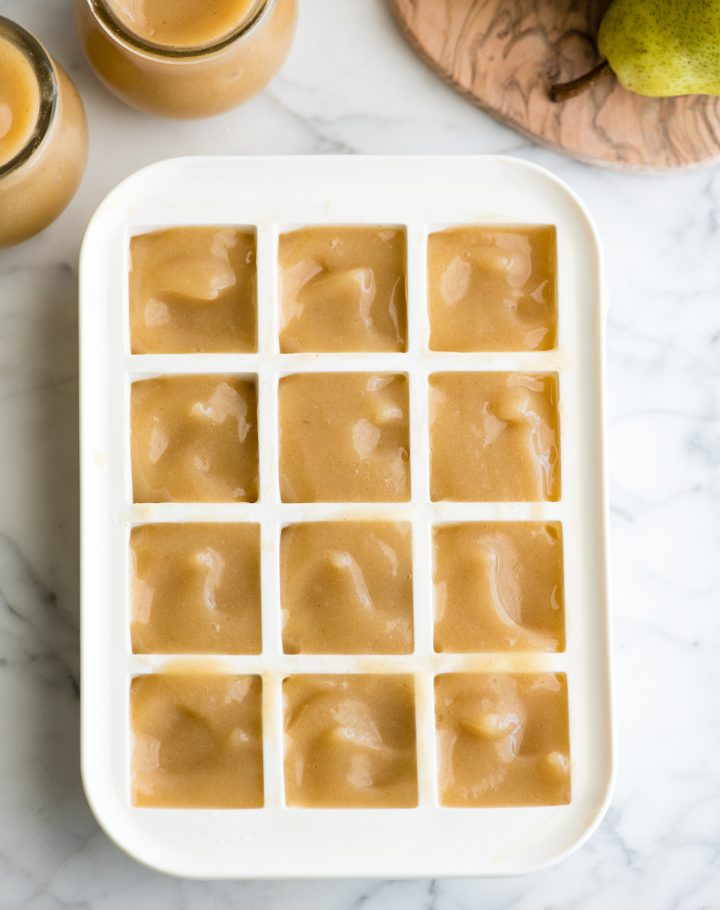 overhead photo showing how to freeze pear baby food in an ice cube tray