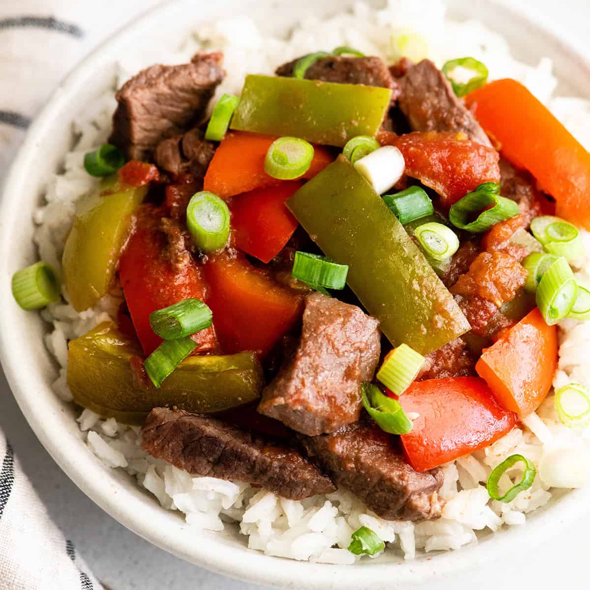 overhead view of slow cooker pepper steak in a bowl over rice
