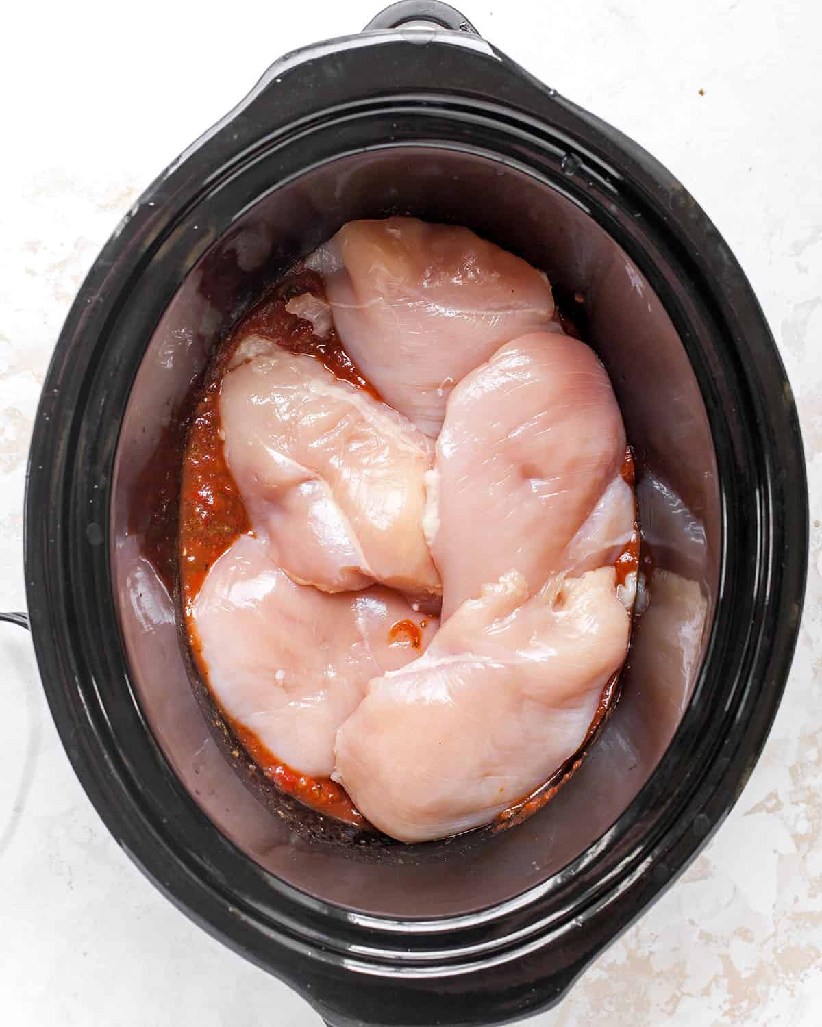 adding chicken breasts to crock pot to make shredded mexican chicken