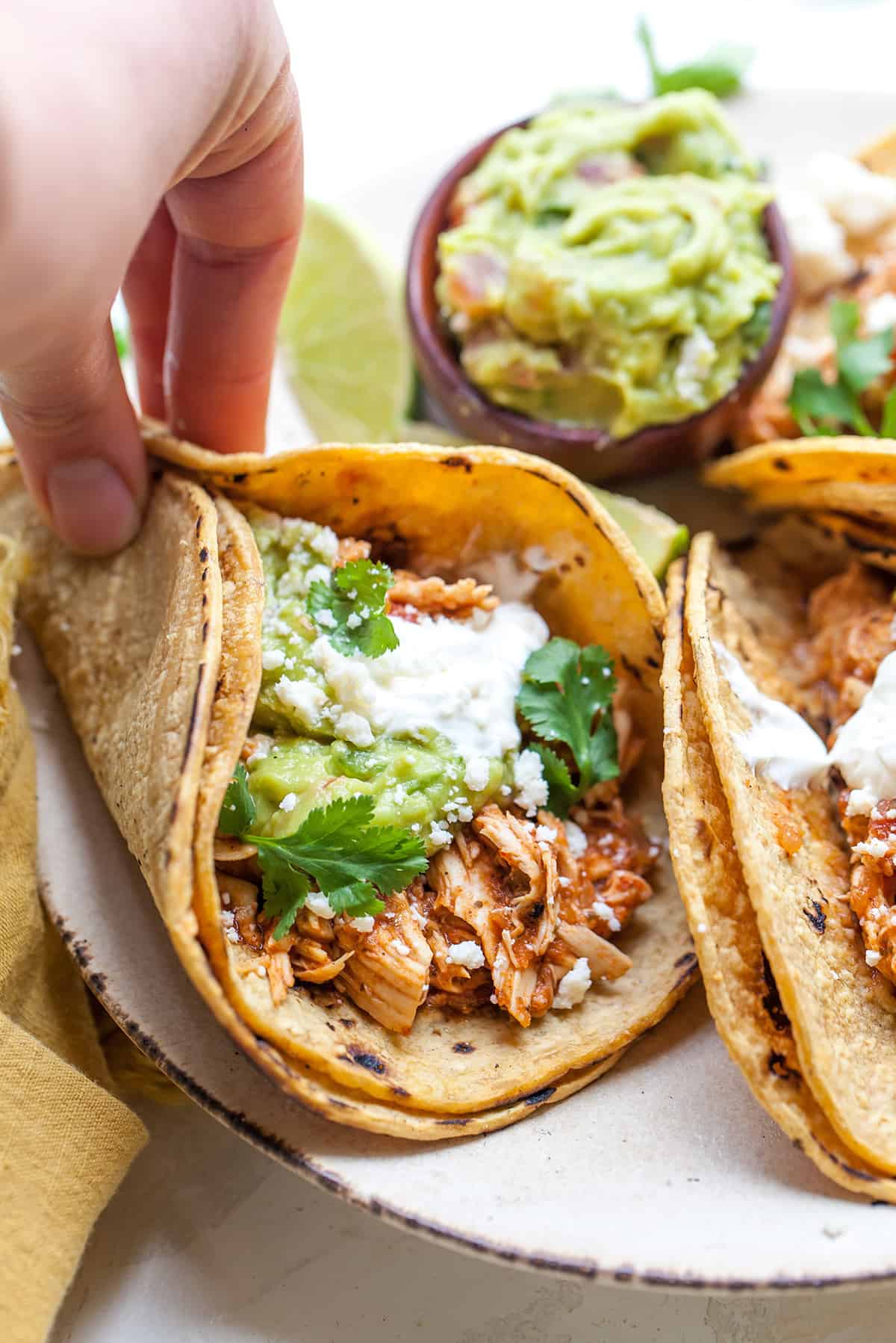 front view of a hand holding a Mexican shredded chicken taco