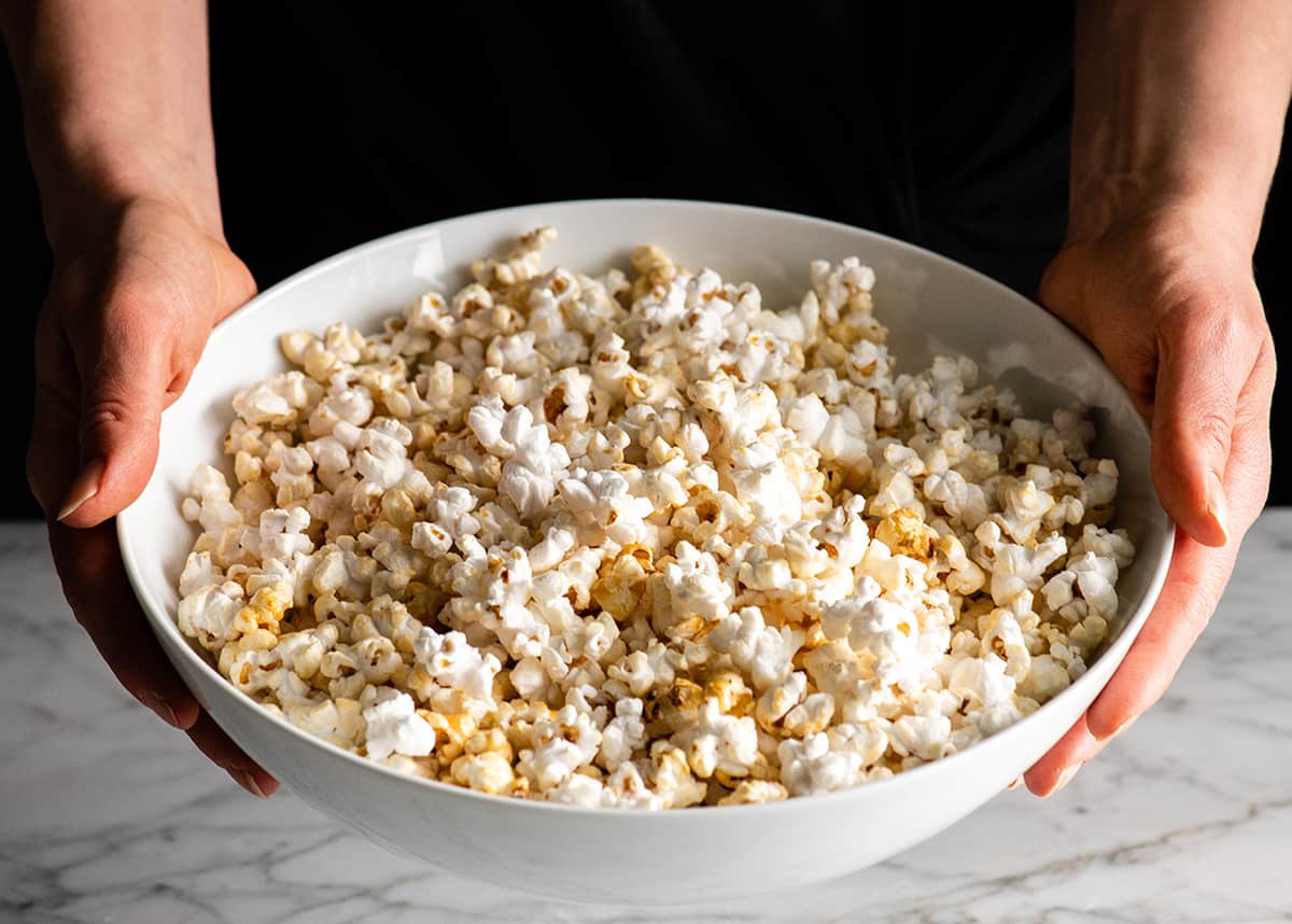 Front view of someone holding a large bowl of homemade kettle corn